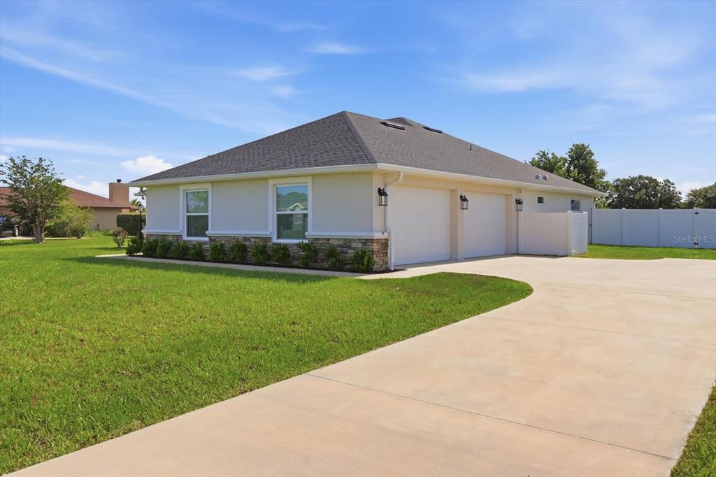 A single-story house with a two-car garage, stone veneer accents, and a concrete driveway — 9811 SE 64TH AVENUE, BELLEVIEW, FL