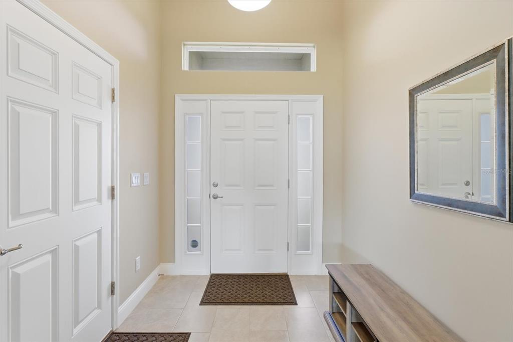 An entryway features a white front door with sidelights, a transom window, and a wall mirror — 9811 SE 64TH AVENUE, BELLEVIEW, FL