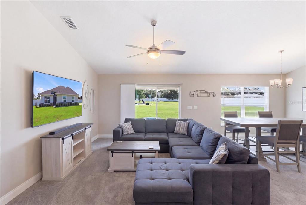 A living room features a gray sectional sofa, a television, and a dining area — 9811 SE 64TH AVENUE, BELLEVIEW, FL