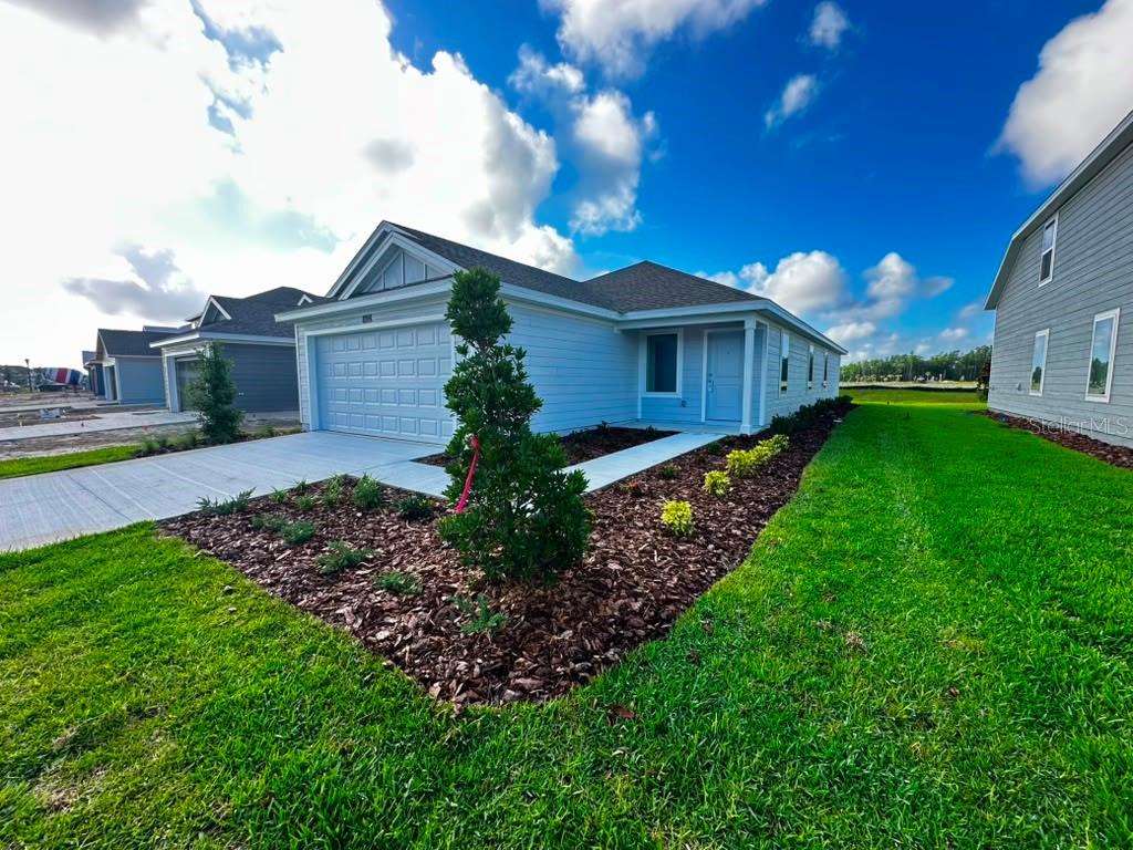 A light blue single-story house with a two-car garage and a landscaped front yard — 5602 MORANT BAY PATH, KISSIMMEE, FL