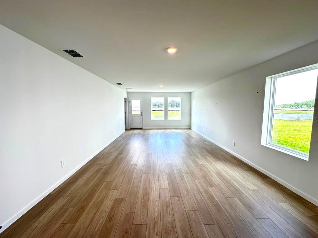 An empty room with light wood-look flooring, white walls, recessed lighting, and a large window — 5602 MORANT BAY PATH, KISSIMMEE, FL