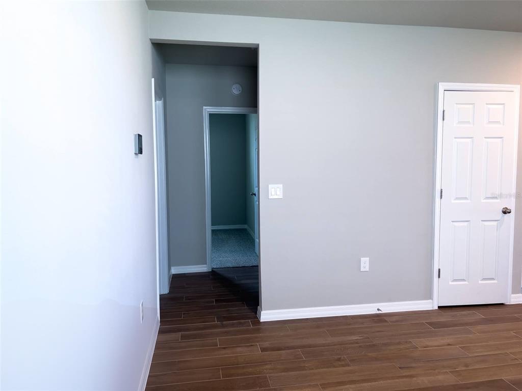 A room with wood-look tile flooring, light gray walls, and a white interior door — 590 AMADORAS WAY, ST CLOUD, FL