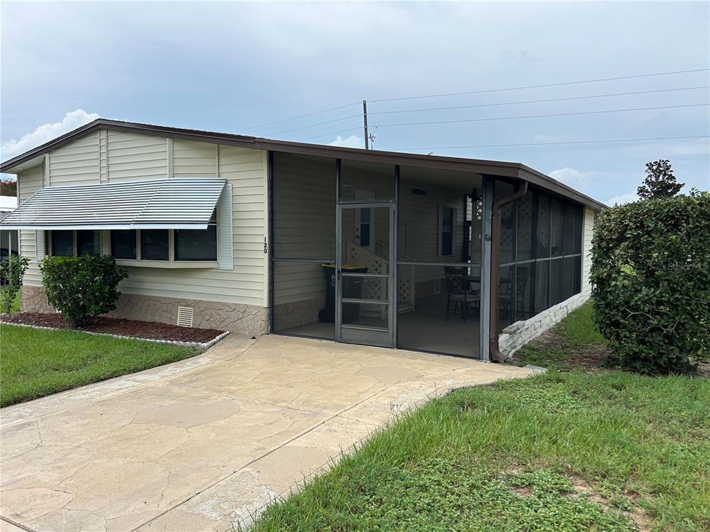 A single-story manufactured home with a screened-in porch and a concrete driveway — 120 KENSINGTON PARK DRIVE, DAVENPORT, FL