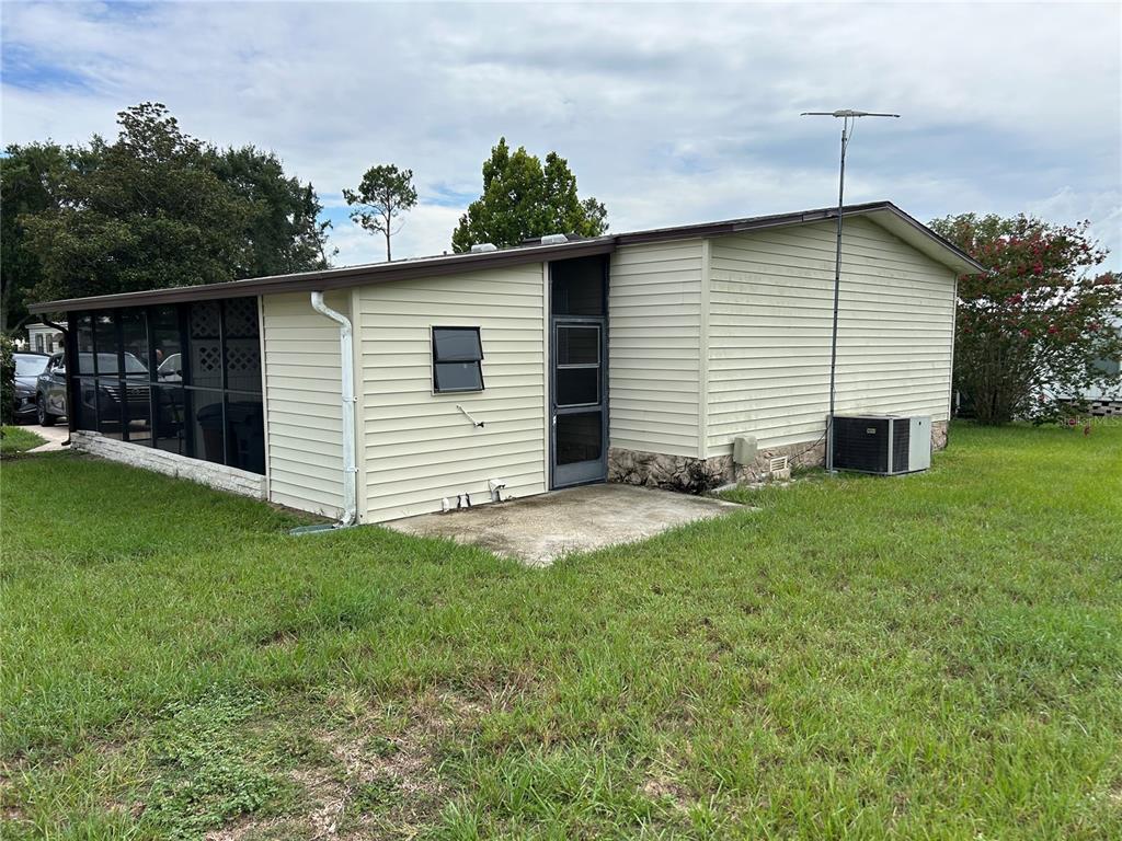 The exterior of a light-colored mobile home features a screened-in porch and a concrete patio — 120 KENSINGTON PARK DRIVE, DAVENPORT, FL