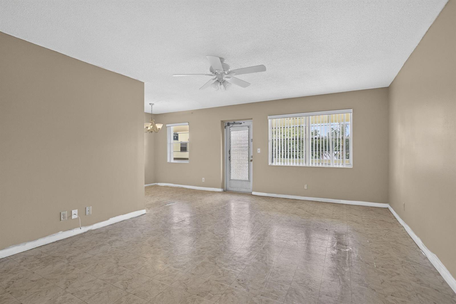An empty living room features beige walls, a ceiling fan, and light-colored tile flooring — 111 Sheffield E, West Palm Beach FL 33417, WEST PALM BEACH, FL
