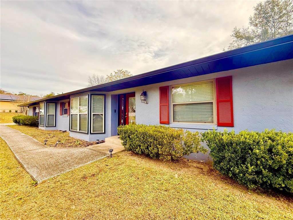 A single-story house with light blue siding, red shutters, and a concrete walkway — 4867 SE 33RD AVENUE, OCALA, FL