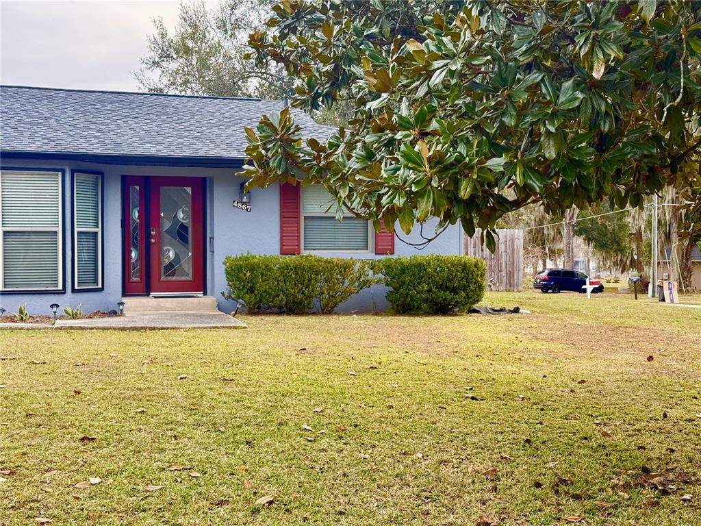 A single-story house with blue siding, red shutters, and a red front door — 4867 SE 33RD AVENUE, OCALA, FL