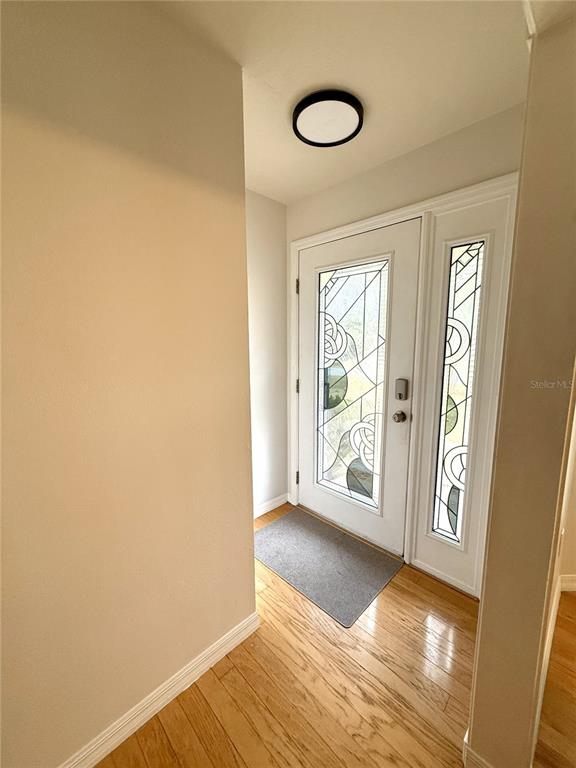 An entryway features a white front door with decorative glass panels and hardwood flooring — 4867 SE 33RD AVENUE, OCALA, FL