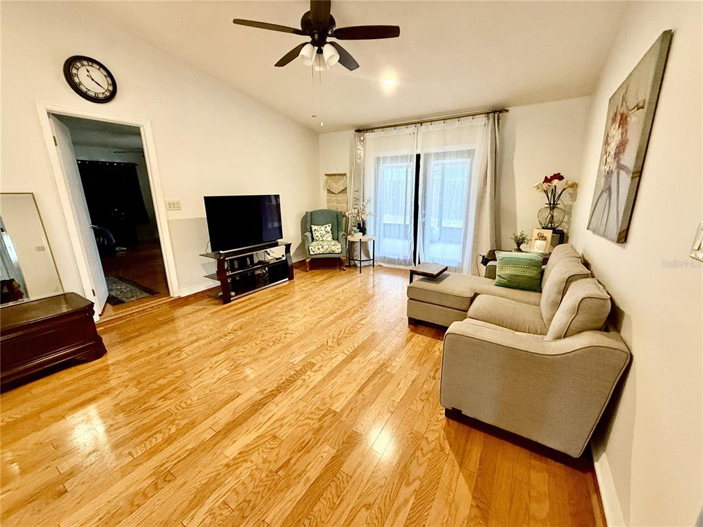A living room features hardwood floors, a sectional sofa, a television, and a ceiling fan — 4867 SE 33RD AVENUE, OCALA, FL