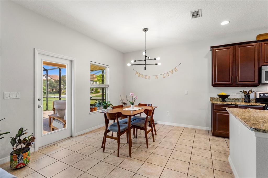 A dining area with tile floors, a modern chandelier, and a view of a patio — 15058 SAWGRASS BLUFF DRIVE, WINTER GARDEN, FL