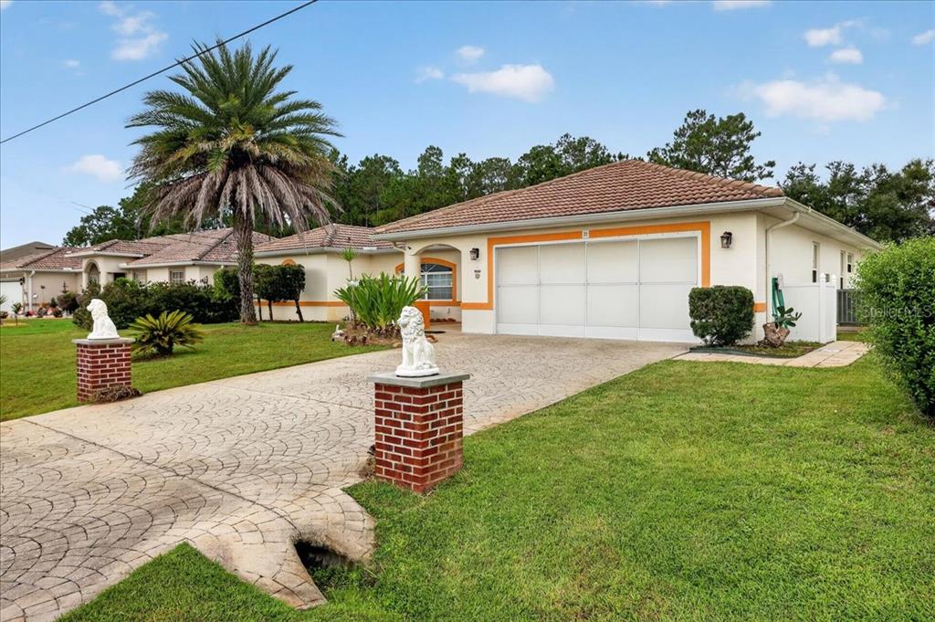 A single-story house with a white garage, brick pillars, and a palm tree in the yard — 28 PRINCETON LANE, PALM COAST, FL