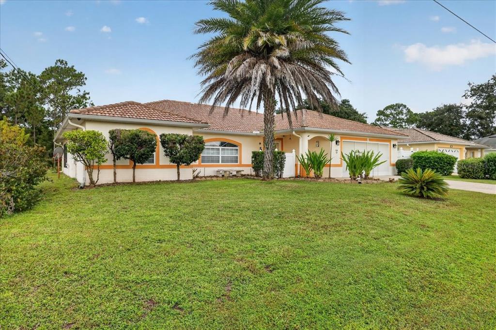A single-story house with a tiled roof, orange trim, and a large palm tree out front — 28 PRINCETON LANE, PALM COAST, FL