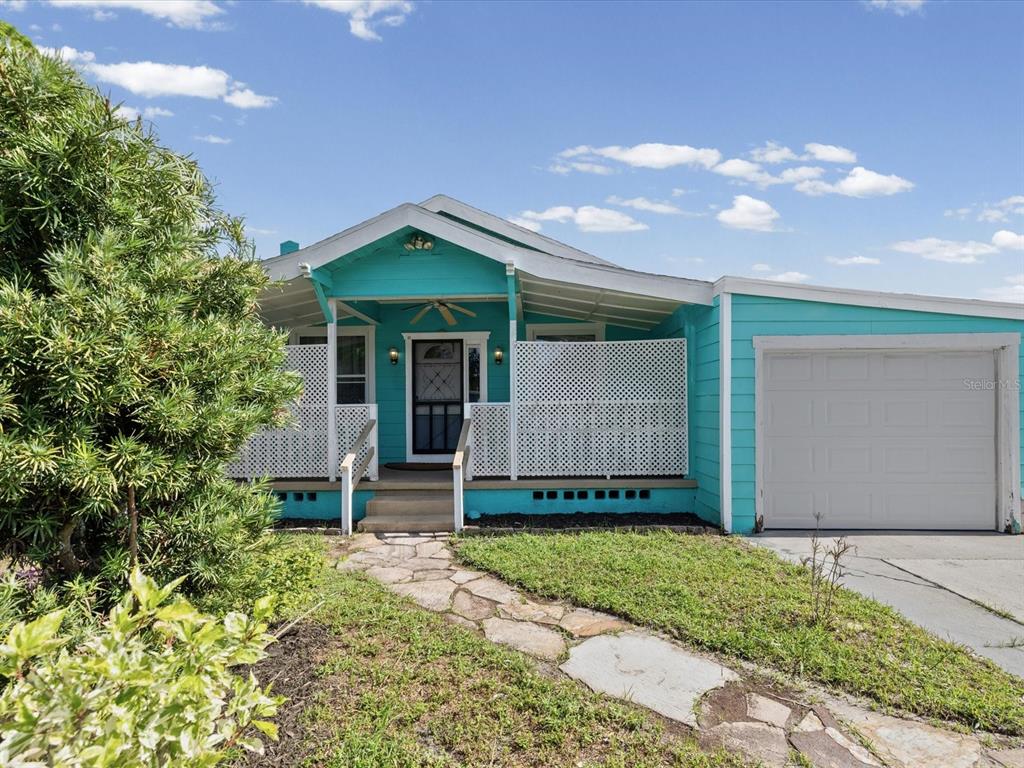 A bright turquoise single-story house features a front porch with white lattice and a garage — 6639 49TH AVENUE N, ST PETERSBURG, FL
