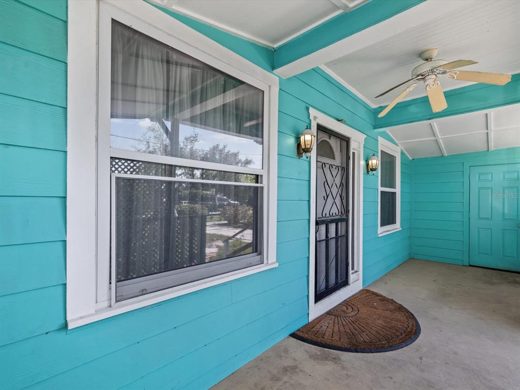 A turquoise-sided porch features a ceiling fan, a screen door, and a concrete floor — 6639 49TH AVENUE N, ST PETERSBURG, FL