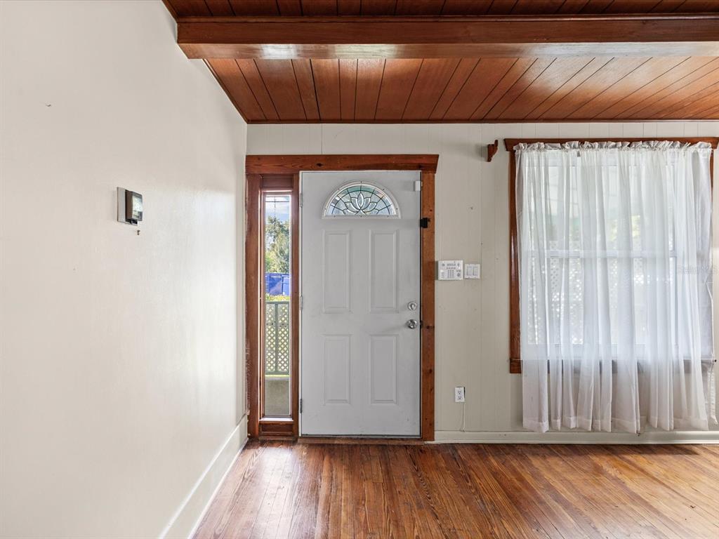 An interior room features wood plank ceilings, hardwood floors, a white front door, and curtains — 6639 49TH AVENUE N, ST PETERSBURG, FL