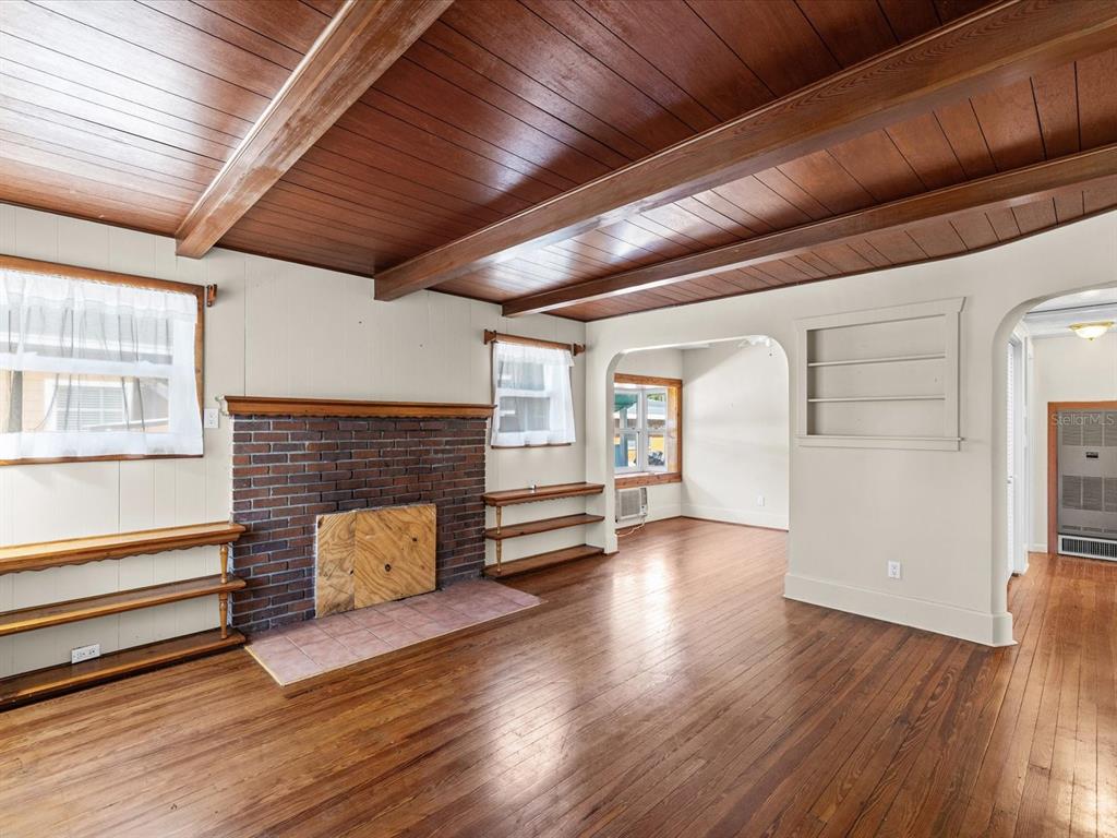 A living room features a brick fireplace, wood-paneled ceiling beams, and hardwood flooring — 6639 49TH AVENUE N, ST PETERSBURG, FL