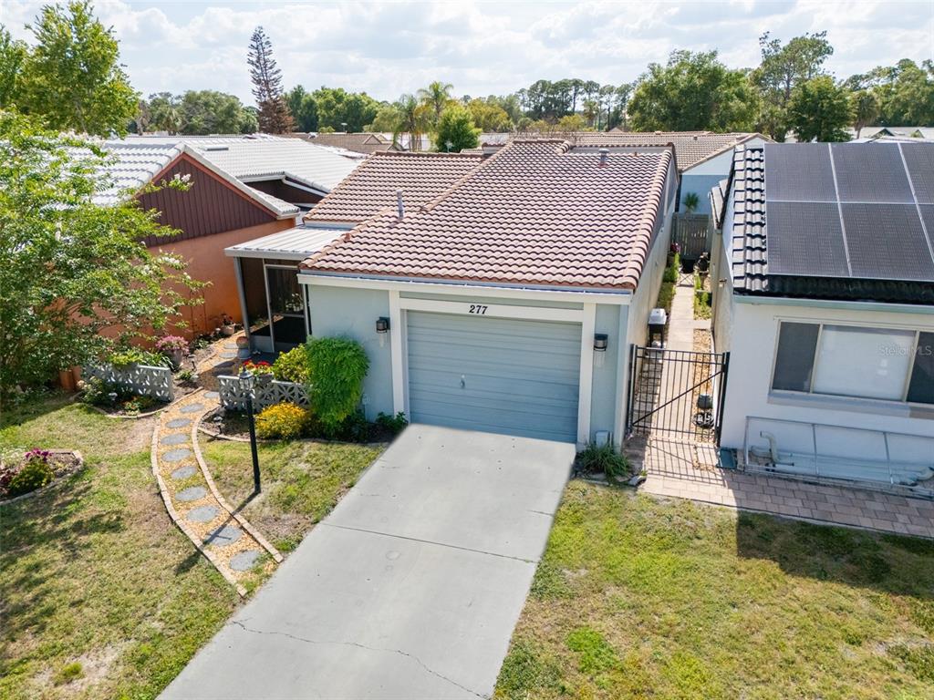 An aerial view shows a single-story house with a tiled roof, garage, and front walkway — 277 MARIPOSA, WINTER HAVEN, FL