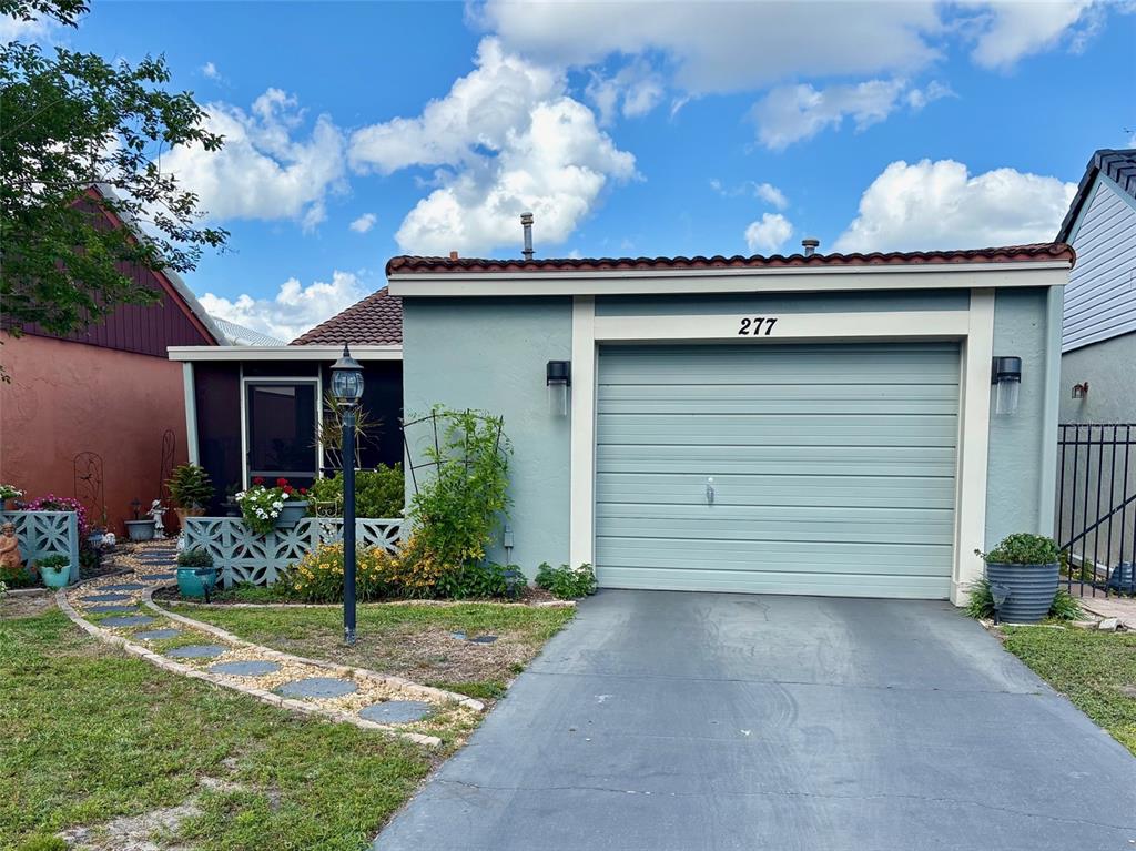 A light blue house features a single-car garage, a screened-in porch, and a stone walkway — 277 MARIPOSA, WINTER HAVEN, FL