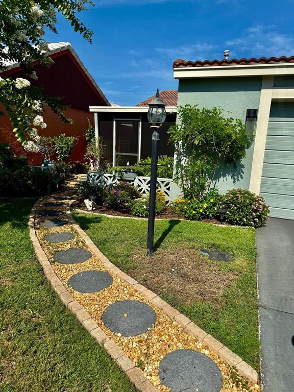 A curved stone walkway leads toward a house with a screened porch and a lamp post — 277 MARIPOSA, WINTER HAVEN, FL