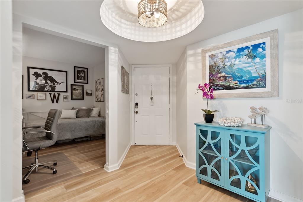 An entryway features light wood flooring, a turquoise cabinet, and a view into a bedroom — 5279 ISLA KEY BOULEVARD S UNIT 212, ST PETERSBURG, FL