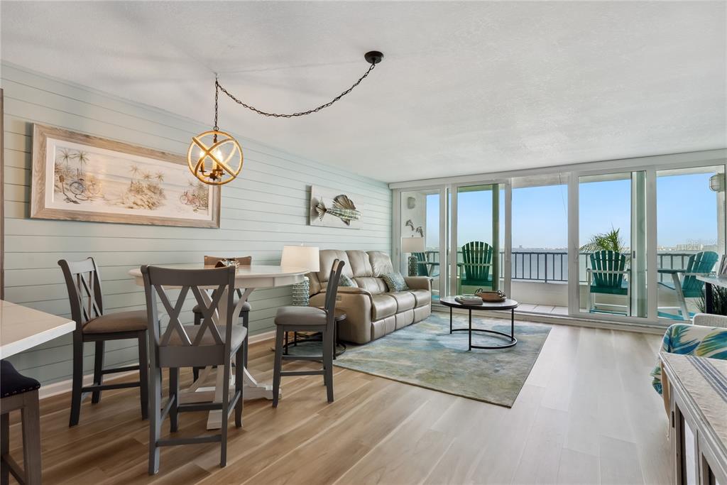 A living and dining area features light wood floors, shiplap walls, and a balcony view — 5279 ISLA KEY BOULEVARD S UNIT 212, ST PETERSBURG, FL