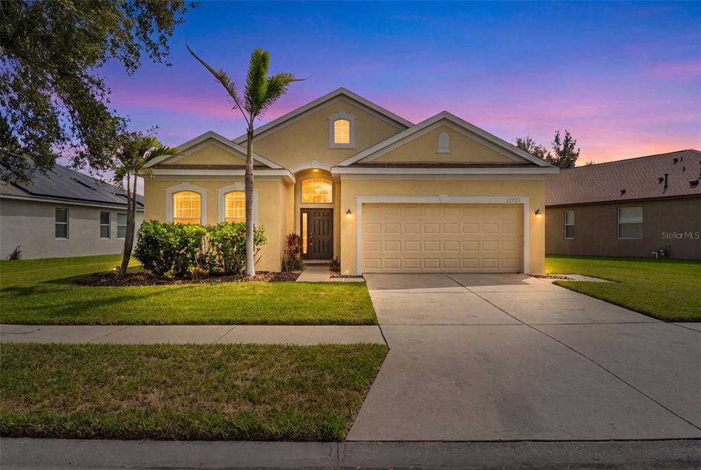 A single-story yellow house with a two-car garage and a palm tree in the yard — 12720 WHITNEY MEADOW WAY, RIVERVIEW, FL