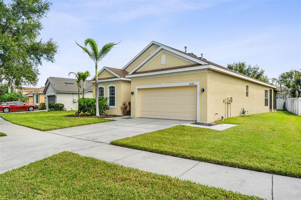 A single-story yellow house with a two-car garage and a palm tree in the yard — 12720 WHITNEY MEADOW WAY, RIVERVIEW, FL