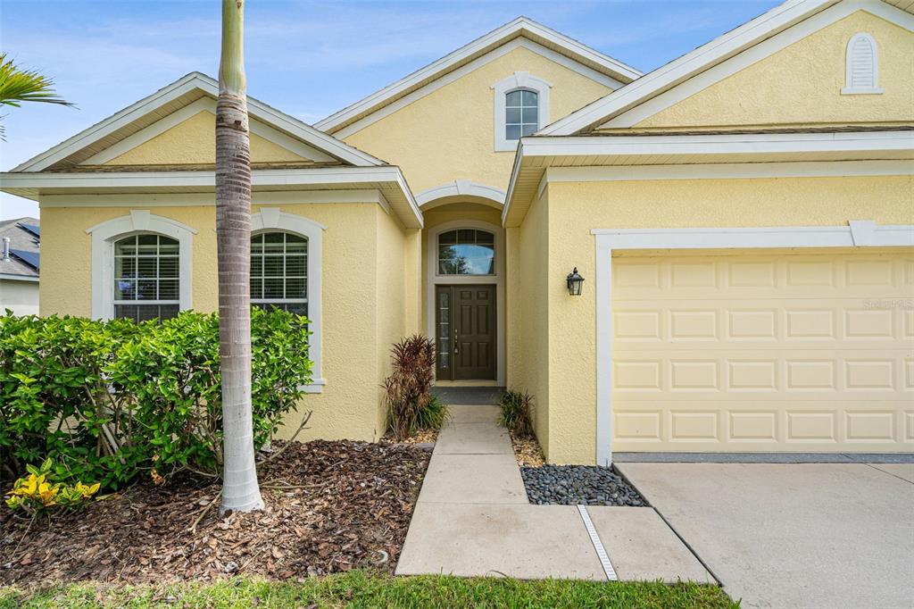 A yellow stucco house with a front walkway, a palm tree, and a two-car garage — 12720 WHITNEY MEADOW WAY, RIVERVIEW, FL