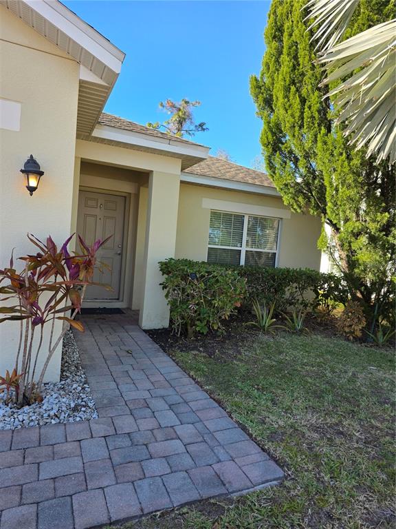 A paved walkway leads to the front entrance of a house with beige stucco walls — 2756 BIG TIMBER DRIVE, KISSIMMEE, FL