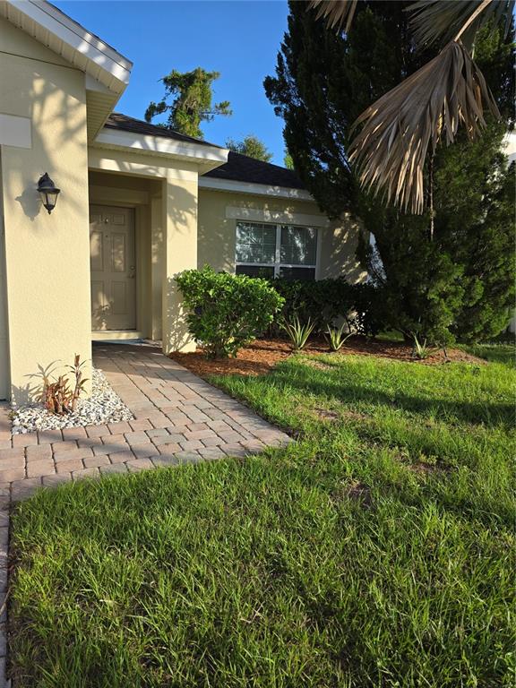 A paved walkway leads to the front entrance of a house with light-colored stucco walls — 2756 BIG TIMBER DRIVE, KISSIMMEE, FL