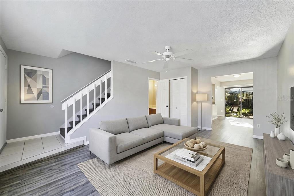 A living room features a gray sectional sofa, a glass coffee table, and a staircase — 605 CASA PARK COURT UNIT H, WINTER SPRINGS, FL