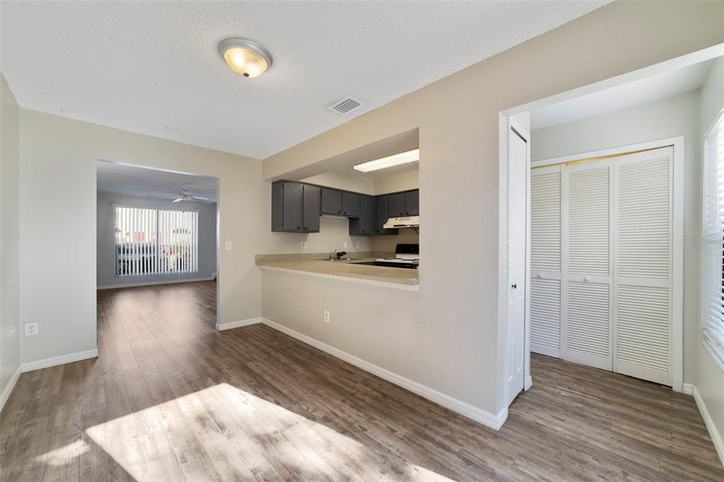 An interior view shows a dining area with wood-look flooring, a kitchen pass-through, and closets — 605 CASA PARK COURT UNIT H, WINTER SPRINGS, FL