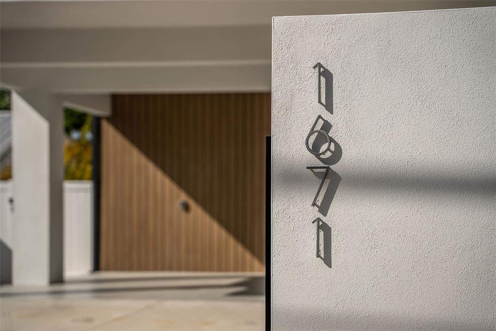A vertical house number sign is mounted on a textured white exterior wall — 1671 ARLINGTON STREET, SARASOTA, FL