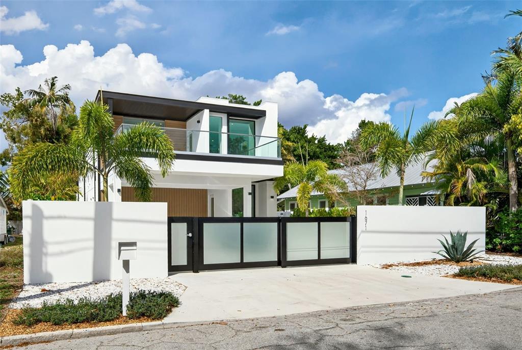 A modern two-story house with a white exterior, glass balcony, and a gated driveway — 1671 ARLINGTON STREET, SARASOTA, FL
