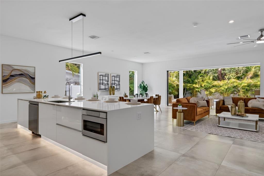 A modern open-concept kitchen and living area with white cabinetry, tile floors, and outdoor views — 1671 ARLINGTON STREET, SARASOTA, FL