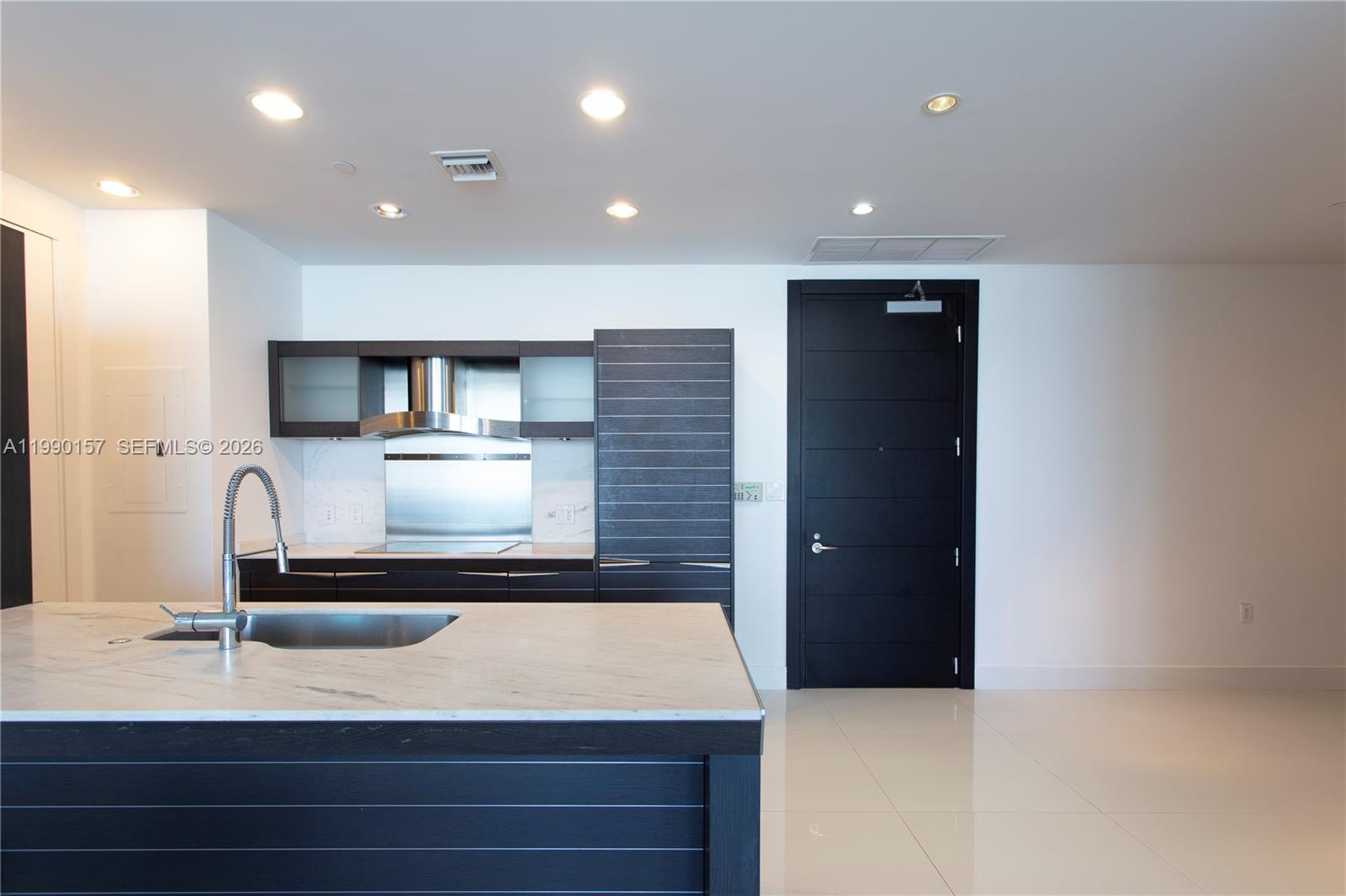 A modern kitchen features a marble-topped island, dark wood cabinetry, and a black door — 200 BISCAYNE BLVD WY # 4512, Miami FL 33131, MIAMI, FL