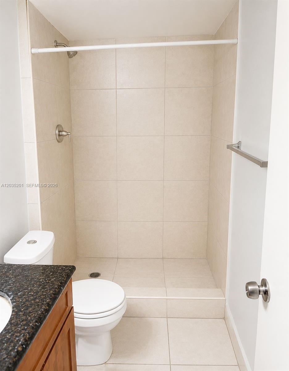 A kitchen features white high-gloss cabinets, stainless steel appliances, and light-colored quartz countertops — 484 NW 165th St Rd # 109, Miami FL 33169, MIAMI, FL