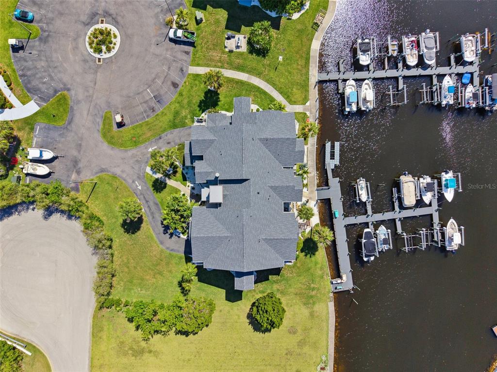 An aerial view shows a building with a gray roof surrounded by a marina and parking — 5712 BISCAYNE COURT UNIT 103, NEW PORT RICHEY, FL