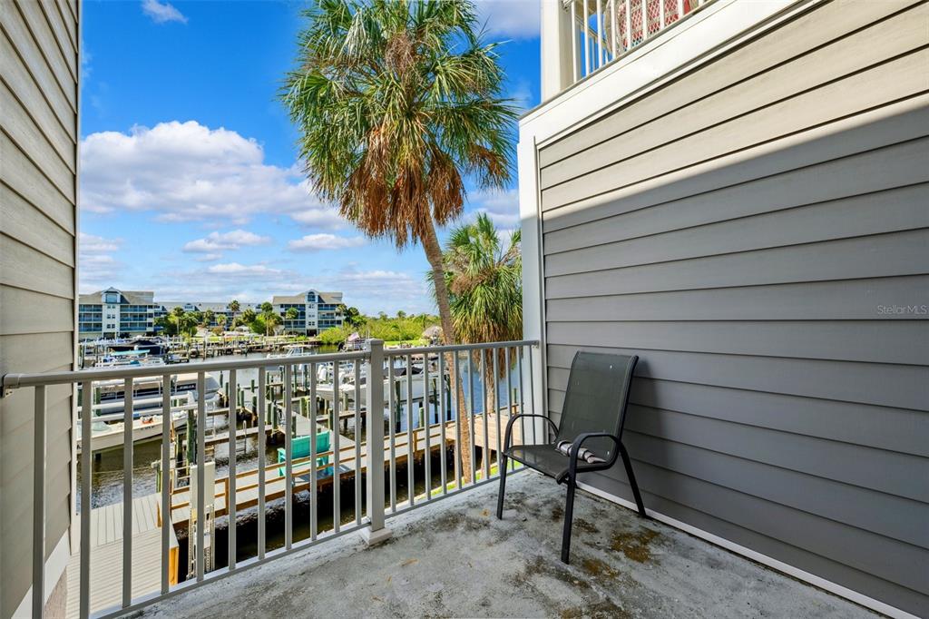 A balcony with a metal railing overlooks a marina with boats and palm trees — 5712 BISCAYNE COURT UNIT 103, NEW PORT RICHEY, FL