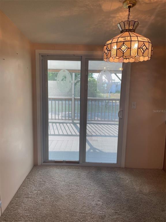 A dining area features beige carpet, a decorative pendant light, and sliding glass patio doors — 29168 CRAWFORD AVENUE, PUNTA GORDA, FL