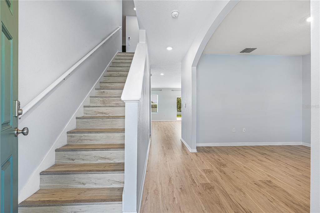 An entryway features a staircase with wood-look treads and light-colored walls leading to an open room — 2731 FIELDBROOKE WAY, EDGEWATER, FL