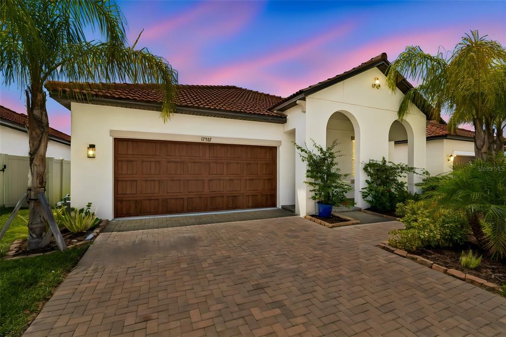 A single-story house with a brown garage door, arched entryway, and a paved driveway — 17307 BLUE WALK STREET, WIMAUMA, FL