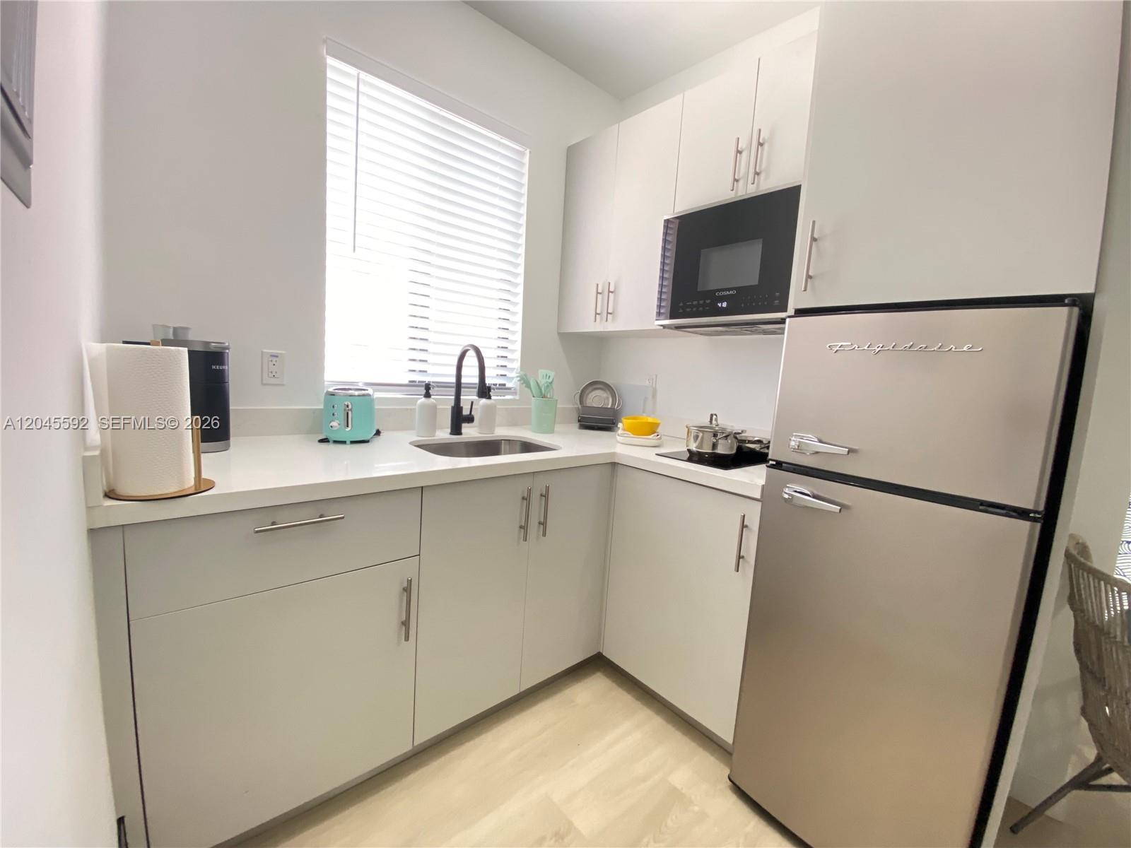 A compact kitchen features white cabinetry, stainless steel appliances, and a retro-style Frigidaire refrigerator — 1553 SW 7th St # 15, Miami FL 33135, MIAMI, FL