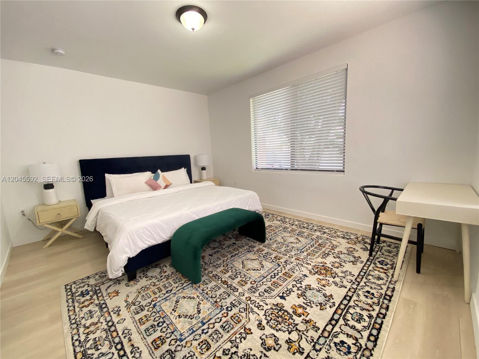 A bedroom features a navy upholstered bed, a green bench, and a patterned area rug — 1553 SW 7th St # 15, Miami FL 33135, MIAMI, FL