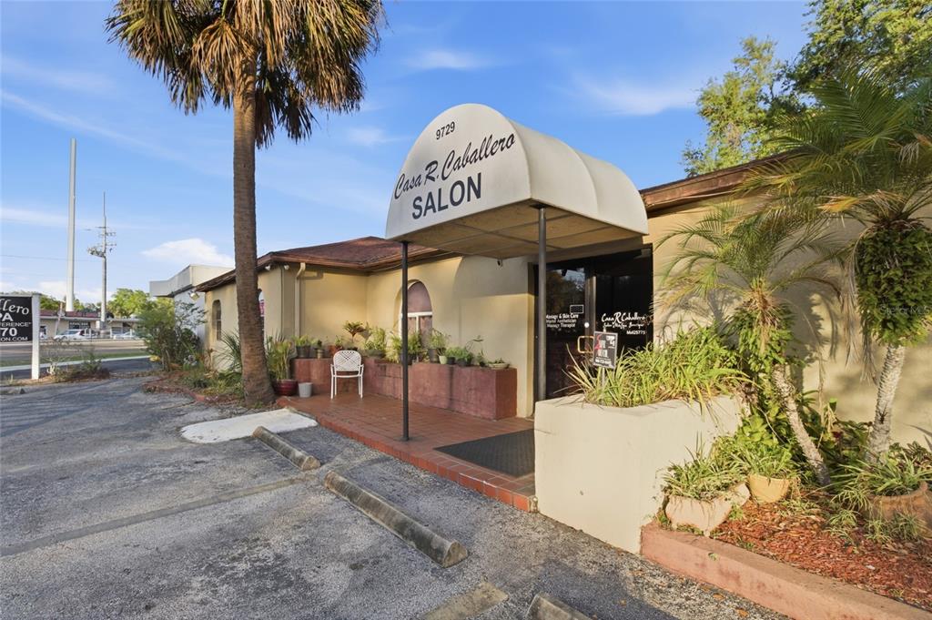 A single-story commercial building with a salon and boutique entrance sits behind a parking lot — 9729 N ARMENIA AVENUE, TAMPA, FL