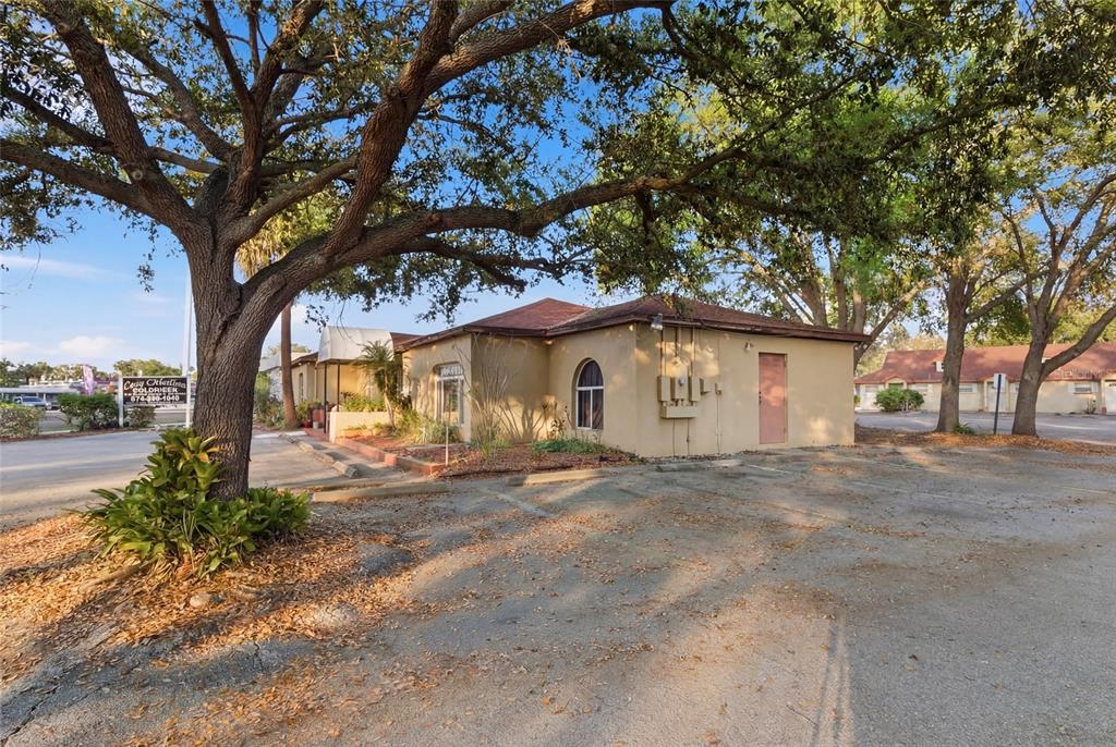 A tan, single-story commercial building with a brown roof sits under large, mature oak trees — 9729 N ARMENIA AVENUE, TAMPA, FL