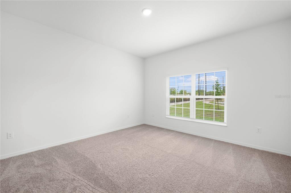 An empty bedroom with white walls, beige carpeting, and a window overlooking a grassy area — 823 PONKAN COURT, BABSON PARK, FL
