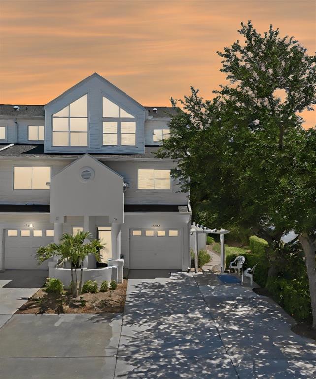 A white multi-story townhouse with a driveway, garage, and a large tree at sunset — 14837 SEMINOLE TRAIL, SEMINOLE, FL