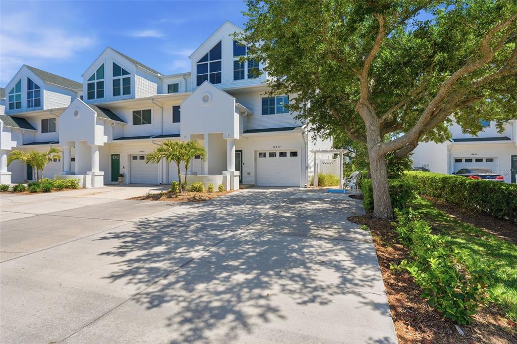 A row of white multi-story townhomes with attached garages and a paved driveway — 14837 SEMINOLE TRAIL, SEMINOLE, FL