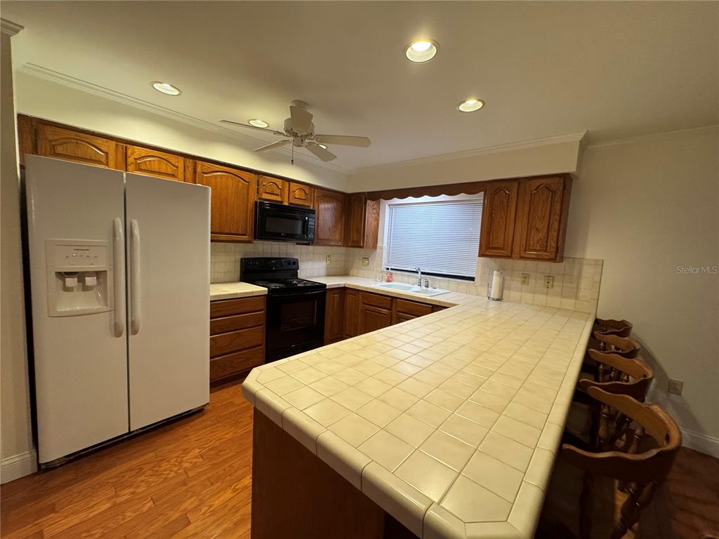 A kitchen features wood cabinets, a tiled countertop, a white refrigerator, and a ceiling fan — 10 FT CLINCH HEIGHTS ROAD, FROSTPROOF, FL